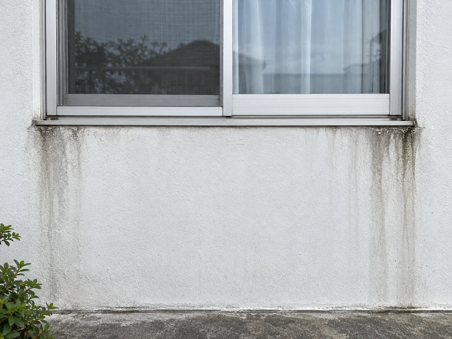 窓の下の壁に雨染みがあるイメージ